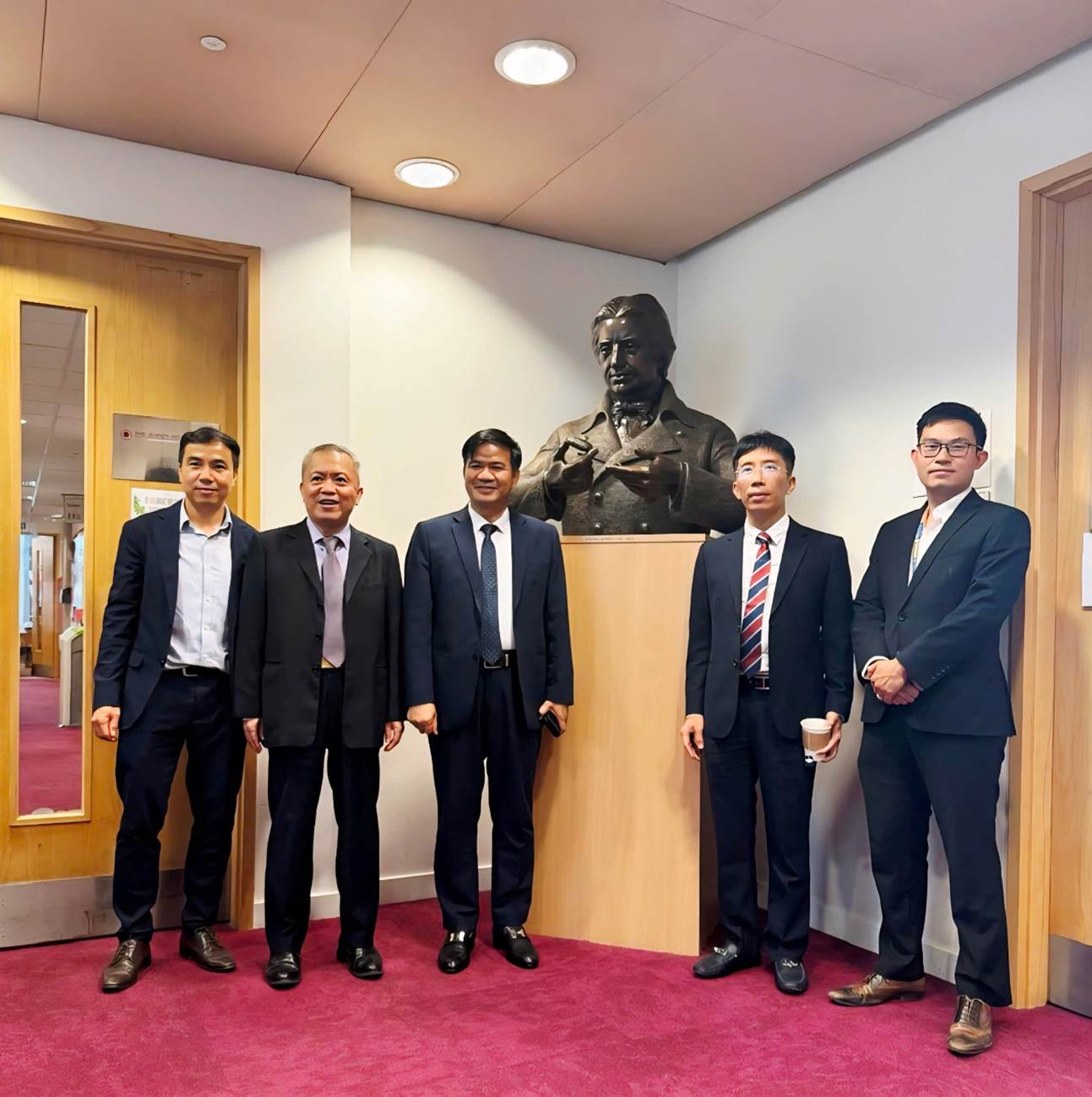 A group of men standing in front of a wall with a statue of a person
AI-generated content may be incorrect.